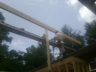 Carpenter setting a ridge beam over a new addition frame — Ice Dam Removal by Roofing Brothers in Bartlesville