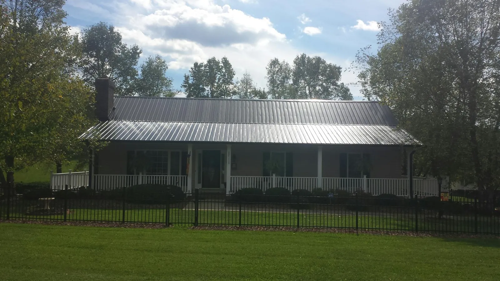 Gray metal roof on a brick ranch with a full width front porch — Gutter Guard Installation work by our crew in Bartlesville