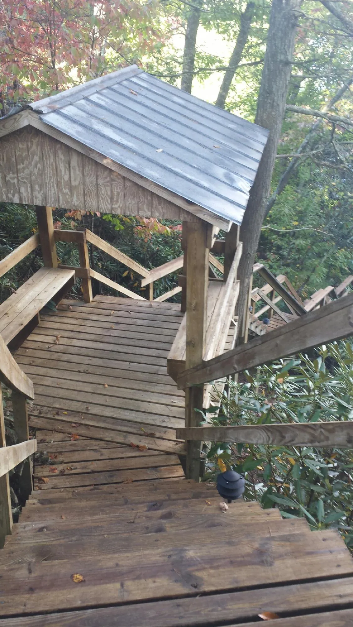 Metal roofed shelter over wooden steps on a wooded walkway — Skylight Repair & Installation work by our crew in Bartlesville