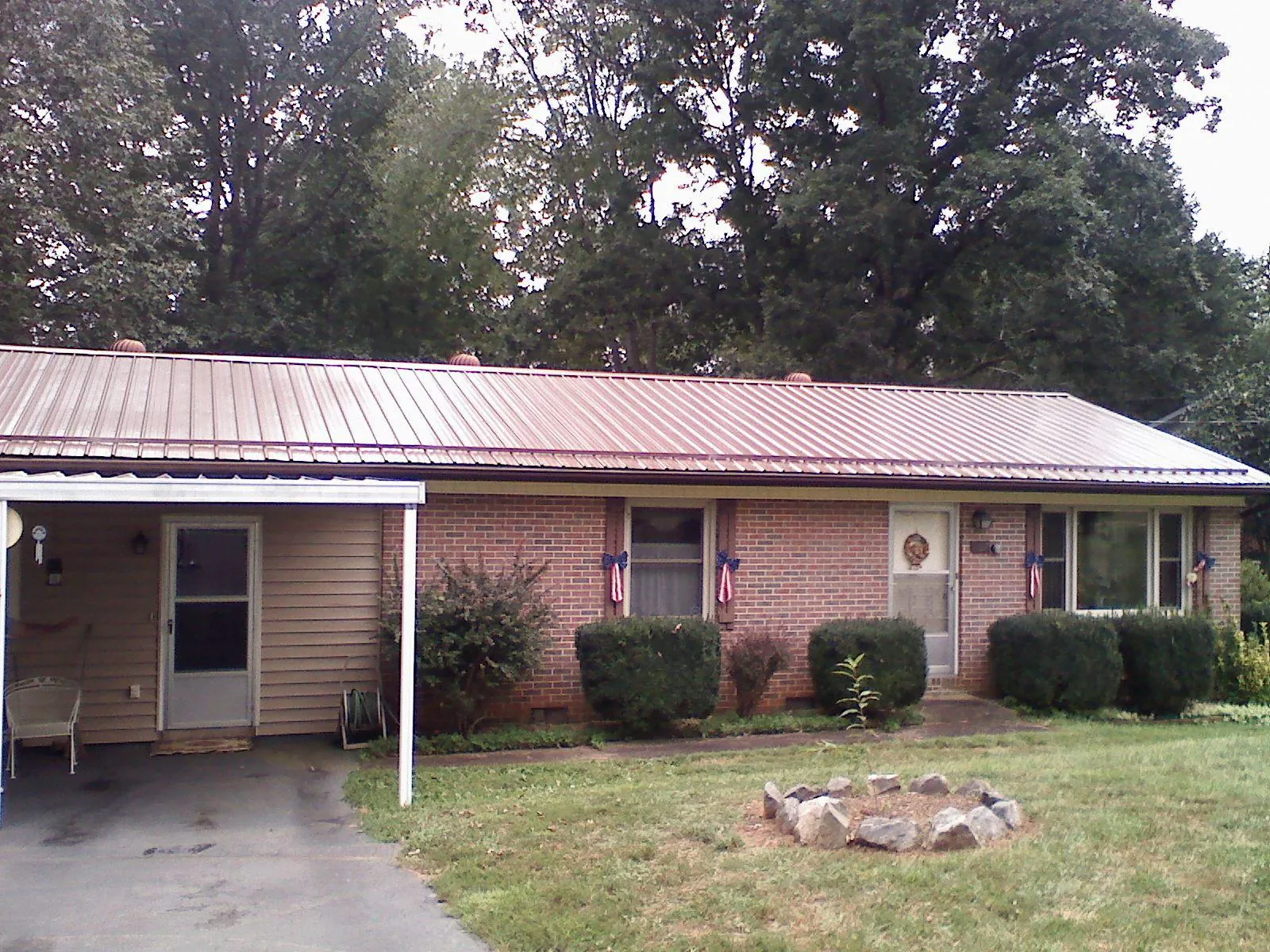 Bronze metal roof and carport on a brick ranch home — Roof Repair work by our crew in Bartlesville